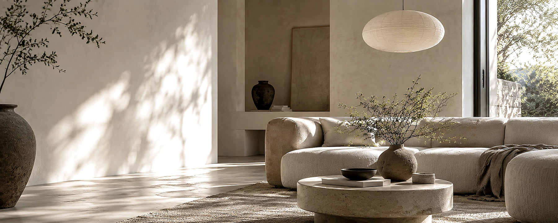 Calm neutral living room with a sculptural rice paper pendant, boucle sofa and travertine table